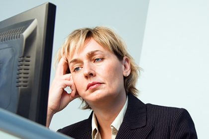 A stressed businesswoman works on a computer, highlighting challenges in the vet sector.