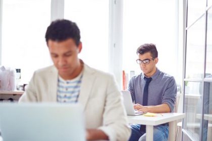 Business professionals collaborate on laptops, highlighting investment in the vet sector.