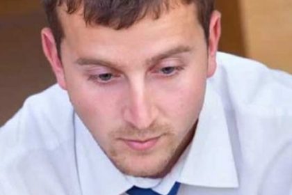 A young man wearing a blue tie considers vet compliance requirements.