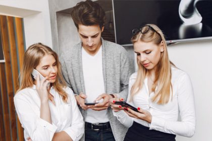 Young professionals collaborating with smartphones in an office setting, highlighting modern vet sector training.