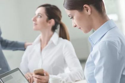 Office workers analyze data on laptops during a business meeting, highlighting vet compliance.