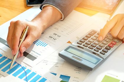 A person performs financial analysis using a calculator and charts, relevant to vet sector funding.