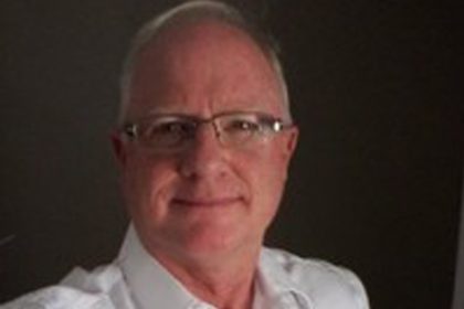 A senior man wearing glasses smiles, representing expert commentary on the vet sector.