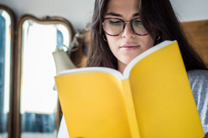 A woman reads a yellow book, representing accessible training resources in the vet sector.