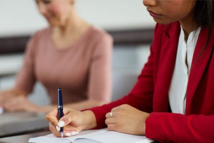 A student diligently takes notes in a classroom, highlighting the importance of quality vet training.