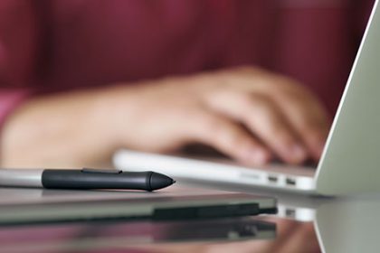 A workstation shows a stylus and graphics tablet used with a laptop for digital training resources.