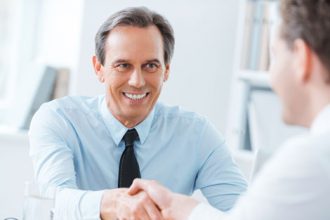 A businessman shakes hands with a candidate during a job interview, highlighting successful vet sector outcomes.