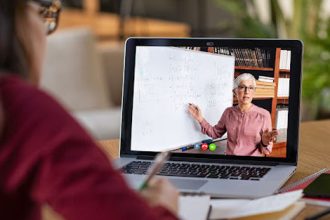 A teacher delivers a lesson via video conference, demonstrating online learning.