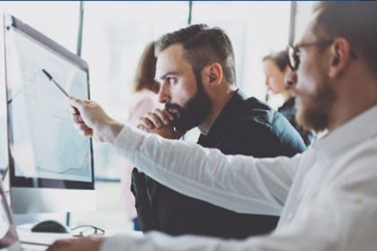 A business team reviews data analysis on a computer, relevant to ASQA’s vet compliance focus.