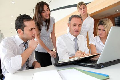 A business team collaborates on a laptop, demonstrating the importance of quality assessment resources.