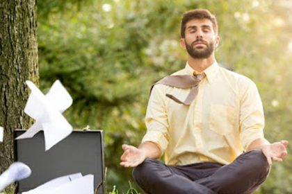 A businessman practices meditation outdoors, finding stress relief while balancing vet sector demands.