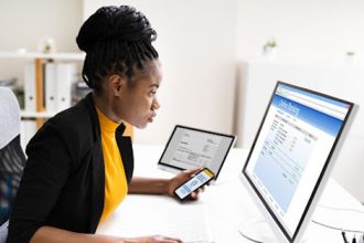 A woman uses multiple devices for online banking, highlighting the need for authentic assessment in vet sector learning.