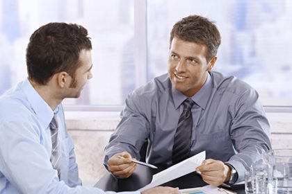 Businessmen reviewing charts and documents during a meeting, highlighting the value of constructive feedback.