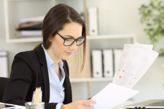 A businesswoman reviews AQF framework documents at her desk.
