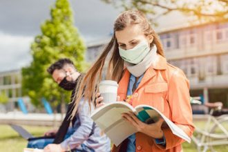 Students wearing face masks study outdoors on a campus, reflecting changes to the vet sector due to COVID-19.