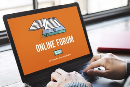 A student uses a laptop to participate in an online forum for vet sector discussions.