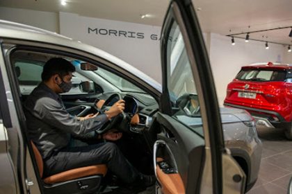 A man examines the interior of a gray MG Hector at a car dealership, demonstrating reasonable adjustments for learners with.