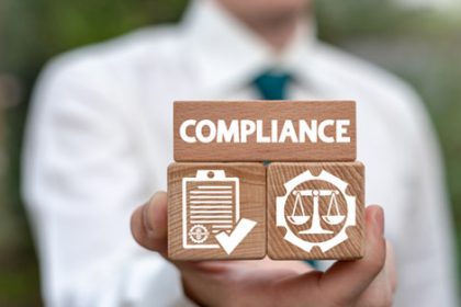 Wooden blocks spell 'Compliance' representing legal requirements for vet sector training.