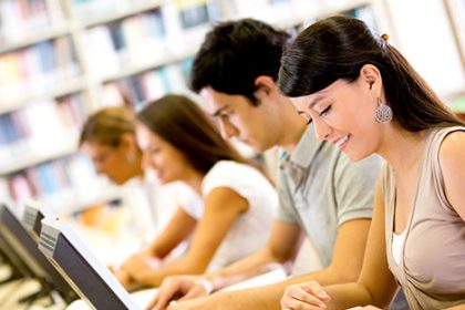 Students researching with computers and books, demonstrating effective e-learning.