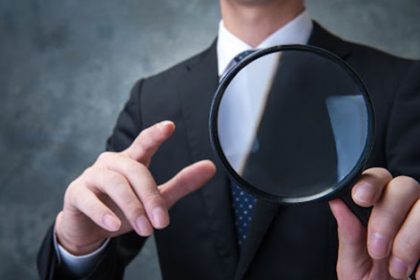 A businessman uses a magnifying glass to review assessment evidence for thorough VET compliance.