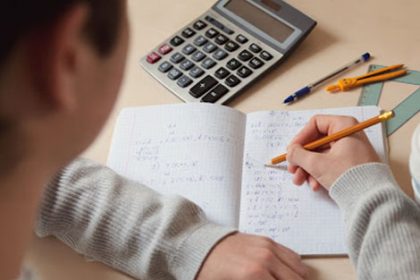 A student uses traditional study tools like a notebook and calculator for vet assessment.