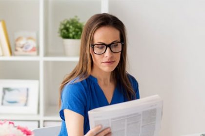 A woman reads a newspaper, representing current news in the vet sector.